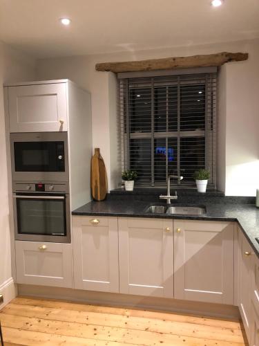 a kitchen with white cabinets and a sink and a window at 4 Quay View, Looe in Looe