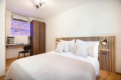 a bedroom with a large white bed with a wooden headboard at Hygge Rooms Split in Split