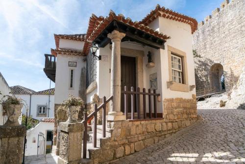 a house with a gate and stairs in a street at Casa Mourisca - Albino d'Óbidos in Óbidos