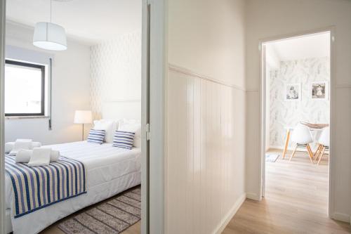 een witte slaapkamer met een bed met blauwe en witte kussens bij Olhos d'Água - Penthouse in Nazaré
