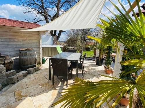 a patio with a table and a white umbrella at Alpenblick Nahe München mit Outdoor Whirlpool - 21 Min von München mit Zug in Aßling