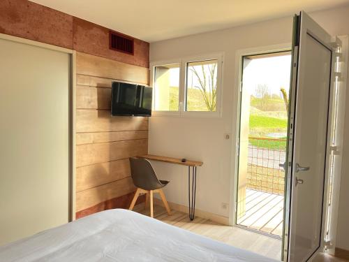 a bedroom with a bed and a desk and a window at Hôtel En Tilleul in Pont-du-Navoy
