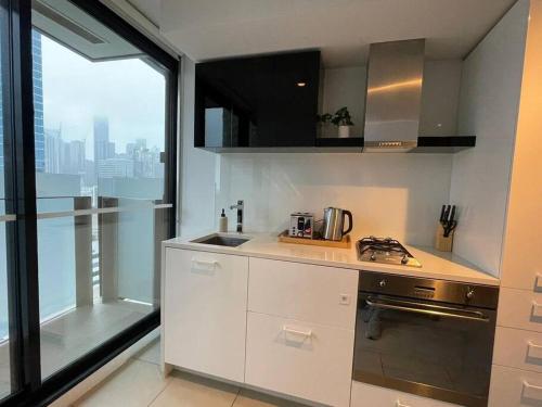 una cucina con armadi bianchi e una grande finestra di City Haven with Breathtaking Views a Melbourne