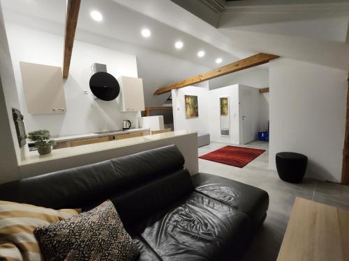 a living room with a black leather couch and a kitchen at Bone ma in Bad Saulgau