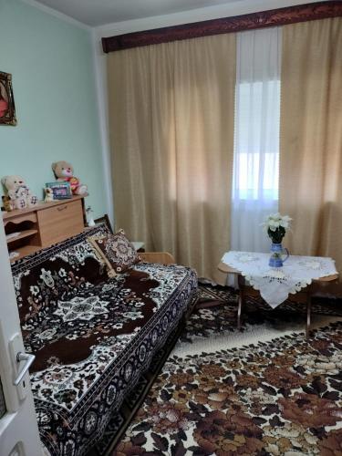 a bedroom with a bed and a table and a window at Casa Tudor-Nicolae in Borşa