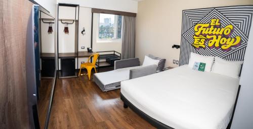 リマにあるibis styles Lima San Isidroのベッド2台とリビングルームが備わるホテルルームです。