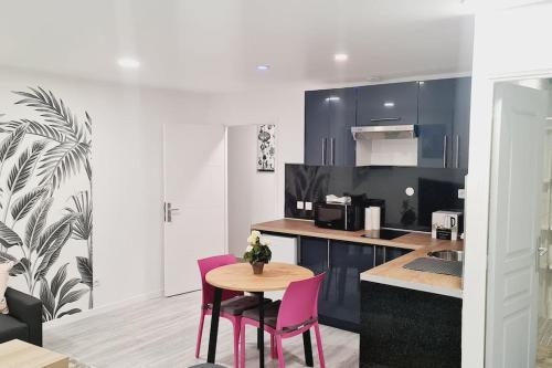 kuchnia ze stołem i 2 różowymi krzesłami w obiekcie Appartement très lumineux et calme. w mieście Sevran