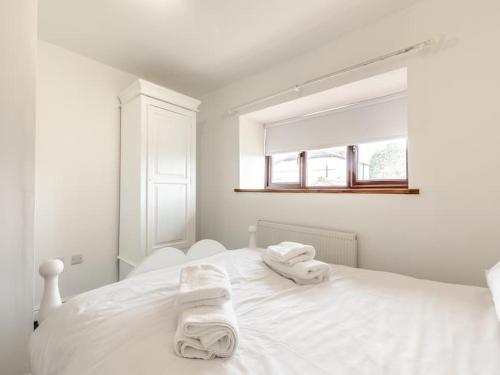 a white bedroom with two towels on a white bed at Stunning Three Bed Cottage - Cottage 3 in Doncaster