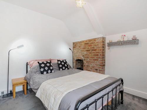 a bedroom with a bed and a brick fireplace at Forge in Newbridge on Wye