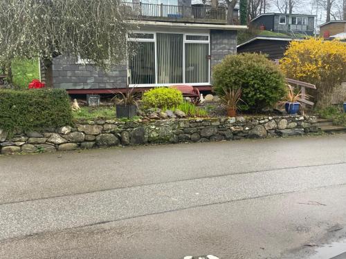 a house with a stone wall next to a street at PEN-Y-FAN HOLIDAY CABIN - GLAN GWNA HOLIDAY PARK SNOWDONIA in Caernarfon