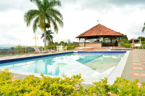 una piscina con cenador y palmeras en FINCA HOTEL TRADICION CAFETERA, en Quimbaya