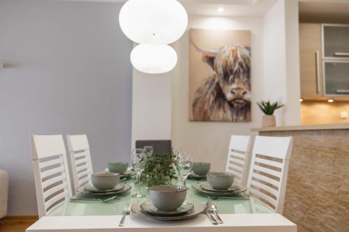 a dining room table with chairs and a picture of a cow at Apartment Marina in Novi Sad