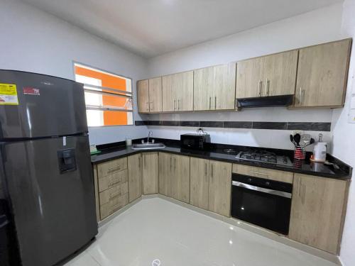 a kitchen with wooden cabinets and a stainless steel refrigerator at CIC APARTAMENTOS cerca UNICOR IMAT in Montería