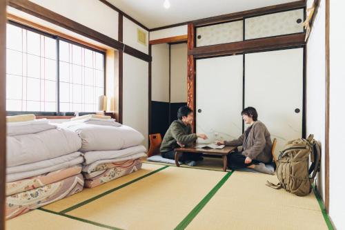 dos personas sentadas alrededor de una mesa en un dormitorio en tabi-shiro, en Matsumoto