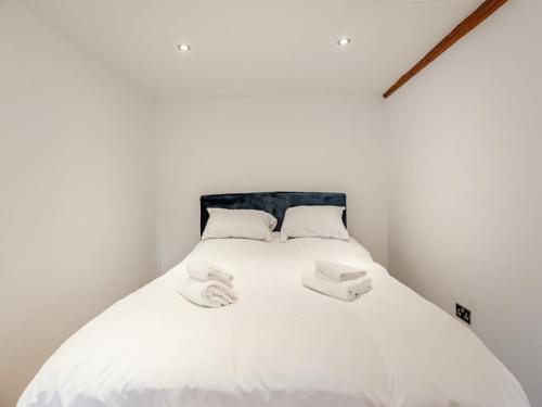 a white bed with two white towels on it at Charming 1 Bedroom Cottage in Doncaster