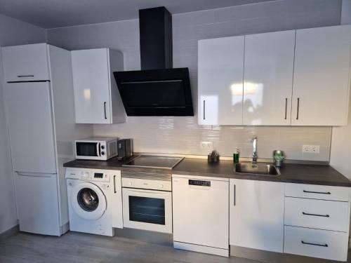 kuchnia z białymi szafkami, zlewem i kuchenką mikrofalową w obiekcie Apartamento mi currilla w mieście Sanlúcar de Barrameda