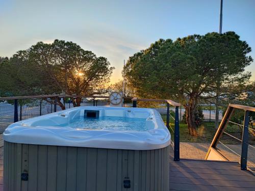 una bañera de hidromasaje en una terraza con vistas a la puesta de sol en el fondo en SEA LUX FLOATING HOUSE AJDA Portorose, en Portorož