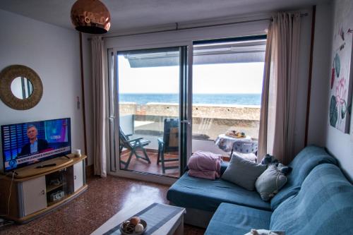 Mar y Sol في لوس كانكاخوس: غرفة معيشة مع أريكة زرقاء وإطلالة على المحيط