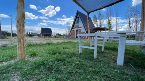 a white picnic table in a field with a barn at Finca Las Liebres in San Rafael