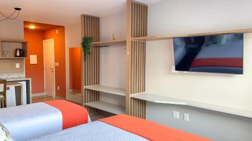 a bedroom with a bed and a tv on a wall at Costa Solar Lagoa in Florianópolis