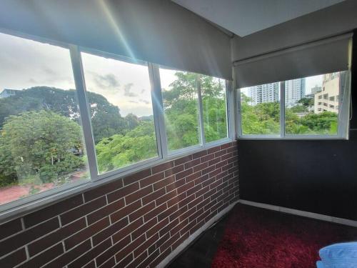 a room with four windows and a brick wall at Rina 1113 Hermoso estudio privado, área turística. in Panama City