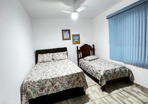 a bedroom with two beds and a window at Cantinho de Maria in Aparecida