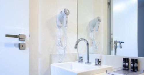 uma casa de banho branca com um lavatório e um espelho em Studio 31 m2 Parque Ibirapuera Itaim Bibi em São Paulo