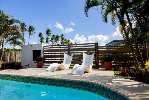 two white chairs sitting next to a swimming pool at Caribbean Backyard - Home w Private Pool/Jacuzzi in Aguada