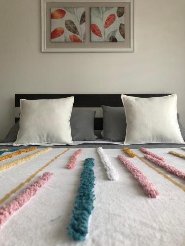 a bed with several different colored pillows on it at Departamento Los Canelos, a metros de Avenida Las Industrias- Incluye, NETFLIX DirecTV aire acondicionado, Internet in Los Ángeles