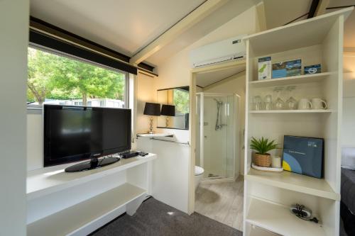 a living room with a large television and a bathroom at Akaroa Top 10 Holiday Park in Akaroa