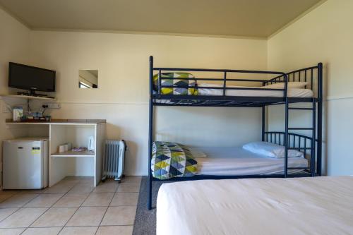 a bedroom with two bunk beds and a television at Akaroa Top 10 Holiday Park in Akaroa