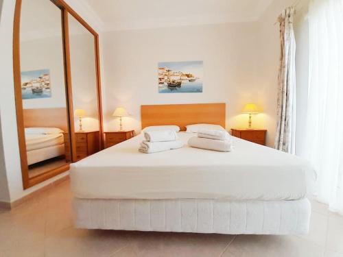 a bedroom with a large white bed with two towels on it at Algarver II-Boavista Golf Fairview Swimpool Apartment in Lagos