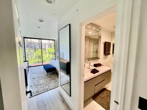 La salle de bains est pourvue d'un grand miroir et d'un lavabo. dans l'établissement Luxury Beverly Hills 24 Hour Security Home 2 Bedrooms Perfect Location, à Los Angeles