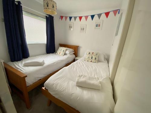 two twin beds in a room with a window at East Coast Chalets 300 Dog friendly at California Sands in Scratby