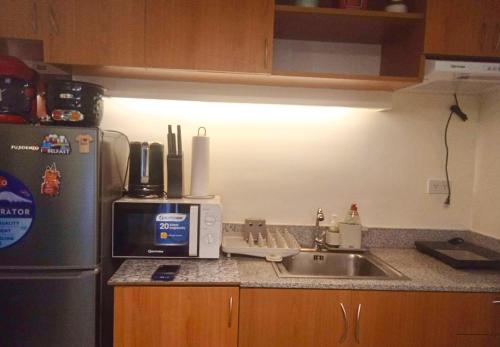 a kitchen with a sink and a refrigerator at Allen’s cozy condo in Davao City