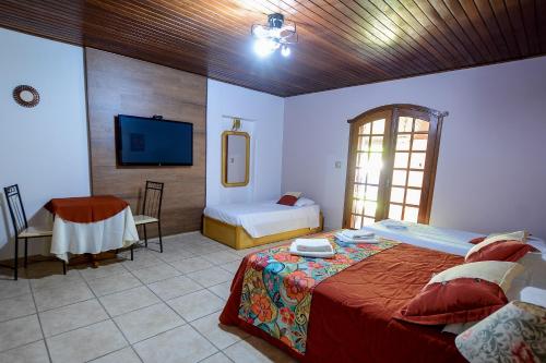 um quarto com duas camas e uma televisão em Biazi Paradise Hotel em Serra Negra