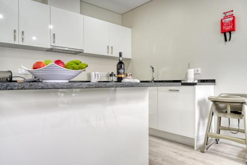 a white kitchen with a bowl of fruit on the counter at Tristão Vaz I, a Home in Madeira in Machico