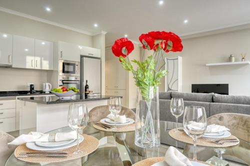 a dining room with red flowers in a vase on a table at Tristão Vaz II, a Home in Madeira in Machico
