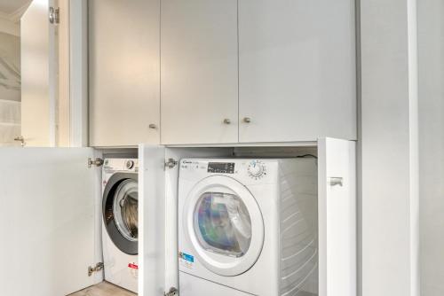 a washer and dryer in a kitchen with white cabinets at Tristão Vaz II, a Home in Madeira in Machico