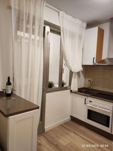 a kitchen with white cabinets and a window with curtains at Casa Dina in Carballino