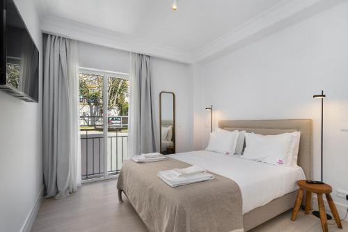 a white bedroom with a bed and a window at Les Deux Mariettes São Bento in Lisbon
