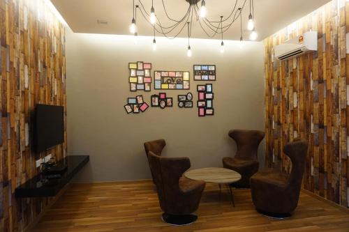 a room with two chairs and a table and a tv at Shamrock Boutique Villa - Stay for 12 person in Batu Ferringhi