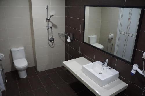 a bathroom with a sink and a toilet and a mirror at Shamrock Boutique Villa - Stay for 12 person in Batu Ferringhi