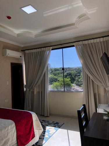 a bedroom with a bed and a large window at Hotel del Parque in Ciudad del Este