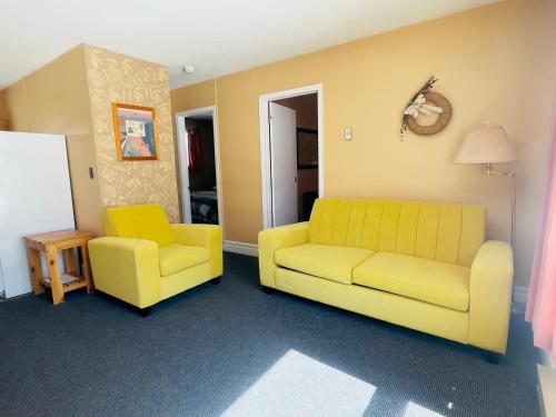 a living room with a yellow couch and two chairs at Glenview Cottages in Sault Ste. Marie