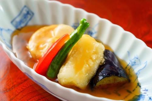 a paper bowl of food with vegetables in a sauce at 由布の里 旅荘 牧場の家 Ryoso Makibanoie in Yufuin