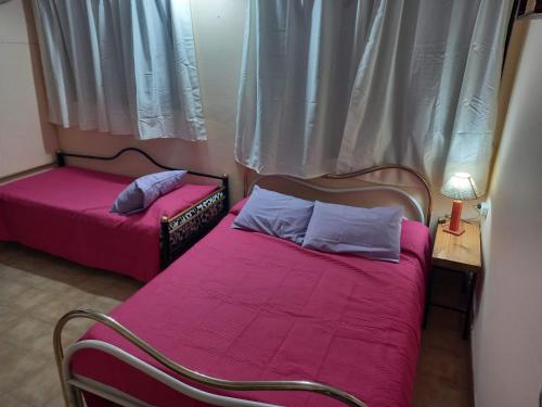 2 camas con sábanas rosas en una habitación con ventana en Descanso en casa de familia en Salta