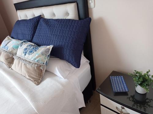 Un dormitorio con una cama con almohadas azules y una mesa. en Apartamento ideal si buscas ubicación y espacio, en Pereira