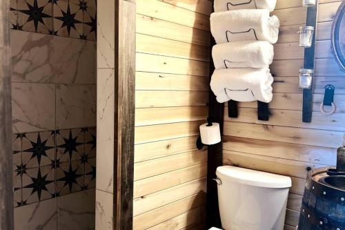 a bathroom with a toilet and towels on a wall at Bourbon Barrel Cottages #1 of 5 on Kentucky trail in Lawrenceburg
