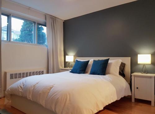 a bedroom with a large white bed with blue pillows at Bright and Spacious Studio Apartment in Montréal